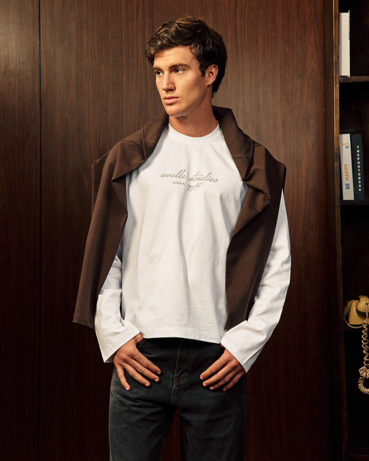 'Avelle Studios' Graphic Printed Long Sleeve Tee In Off White, front, styled with a brown layer over the shoulders